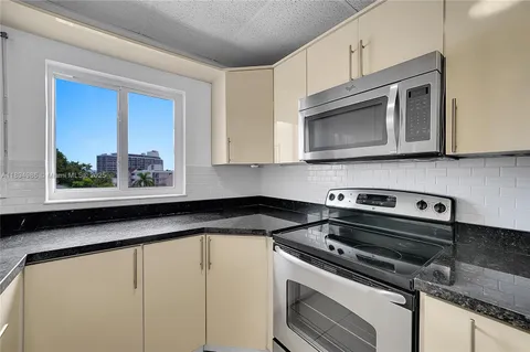 a kitchen with granite countertop cabinets stainless steel appliances and a window