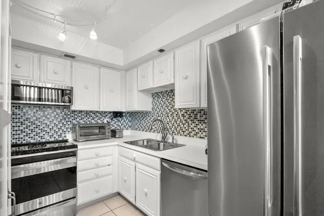 a kitchen with white cabinets sink and stainless steel appliances