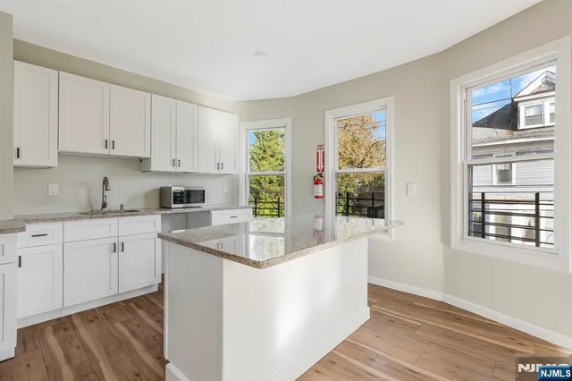 a kitchen with stainless steel appliances granite countertop a sink and a granite counter tops with wooden floors