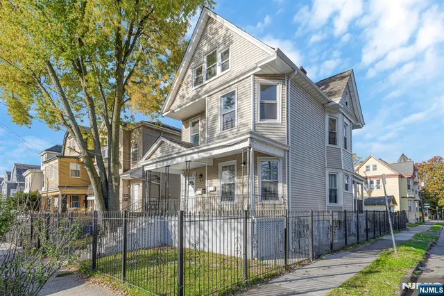 a view of a white house with iron fence