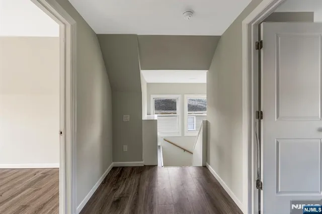 a view of a hallway with wooden floor and a kitchen
