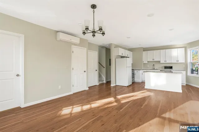a view of a kitchen with refrigerator and wooden floor