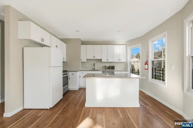 a kitchen with a refrigerator a stove top oven and a wooden floor