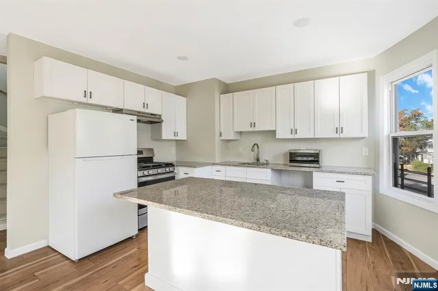 a kitchen with granite countertop a refrigerator and a sink