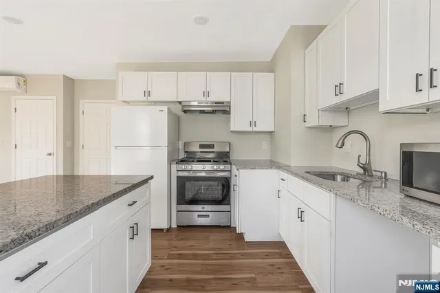 a kitchen with granite countertop a sink stove and refrigerator