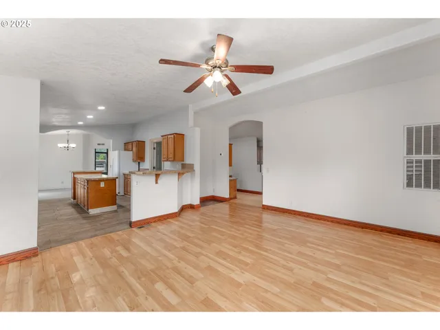 a view of a livingroom with a kitchen island stainless steel appliances wooden floor and a window