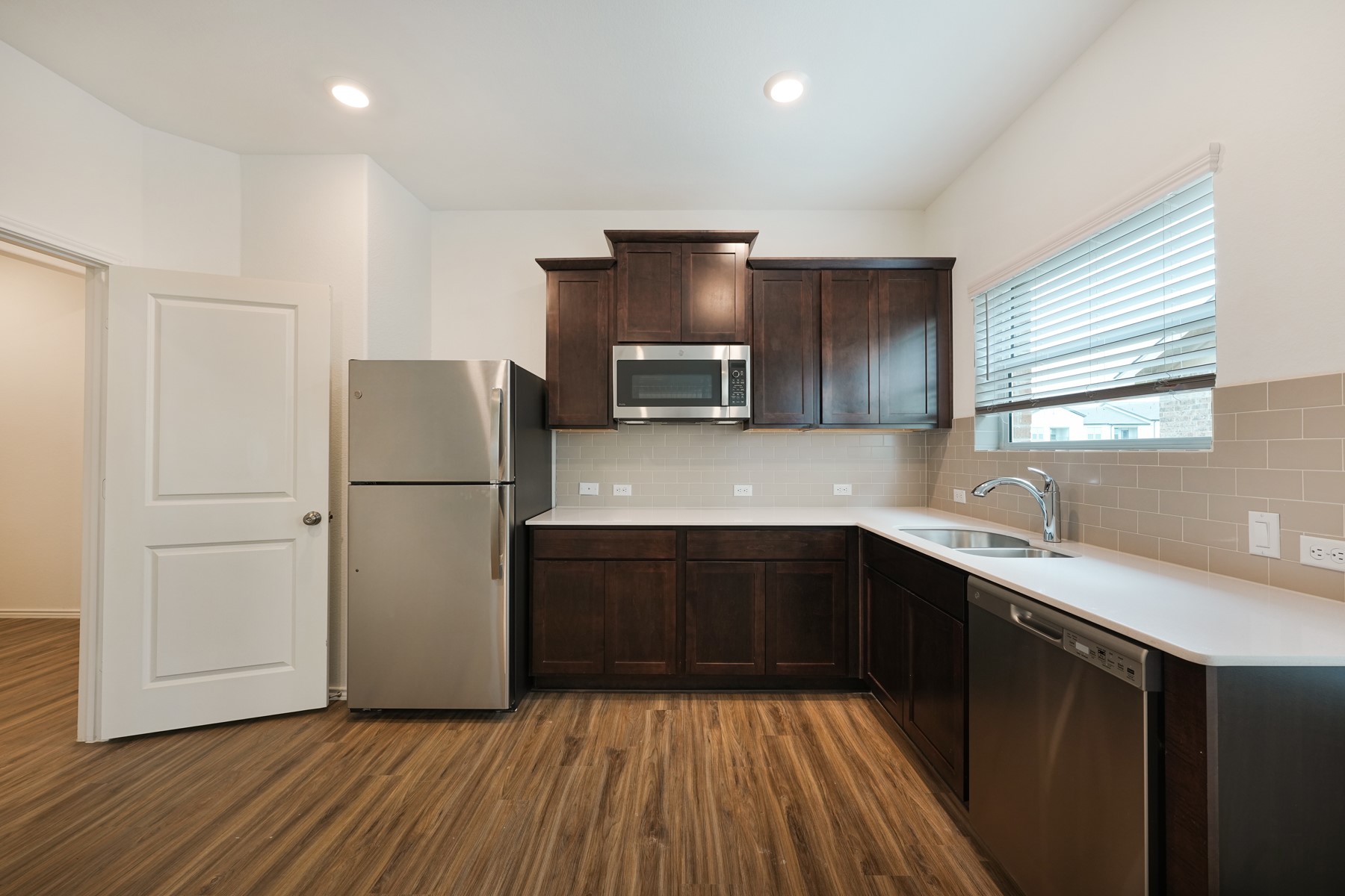 932 Mallow Road Leander, TX 78641 - Photo 4 of 34 This kitchen showcases durable laminate flooring, sleek white countertops, and modern dark wood cabinetry.