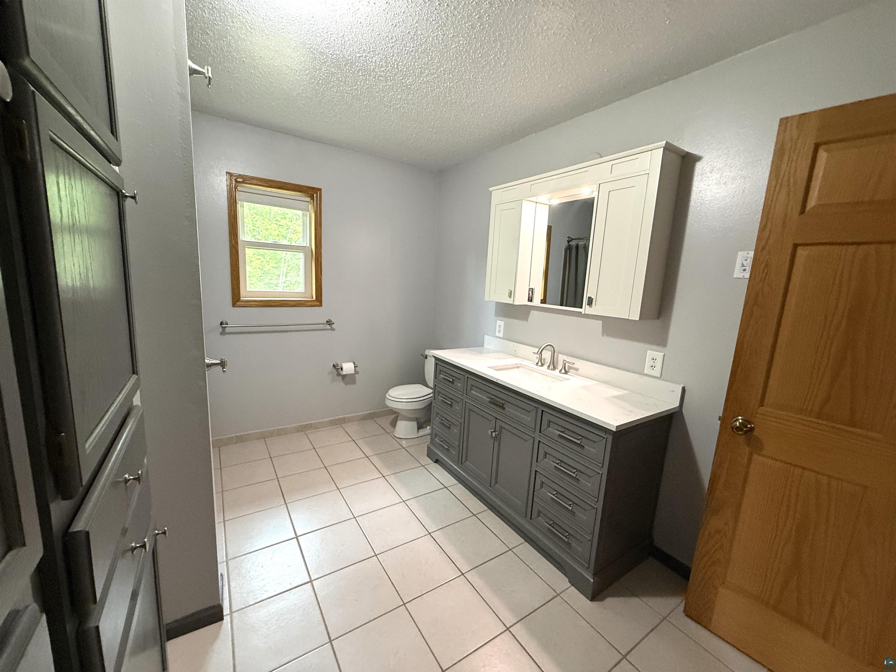5080 Tower Road Moose Lake, MN 55767 - Photo 27 of 49 Gray vanity with a white countertop and rectangular sink, white medicine cabinet, and tile flooring