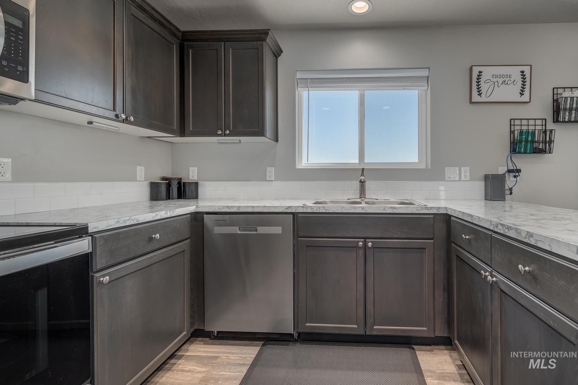 1049 Price Road Weiser, ID 83672 - Photo 10 of 47 Kitchen featuring dark wood-finish cabinetry, light-toned countertops, subway tile backsplash, stainless steel appliances, and wood-finish flooring