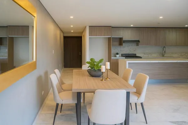 a dining room with furniture a potted plant and kitchen view