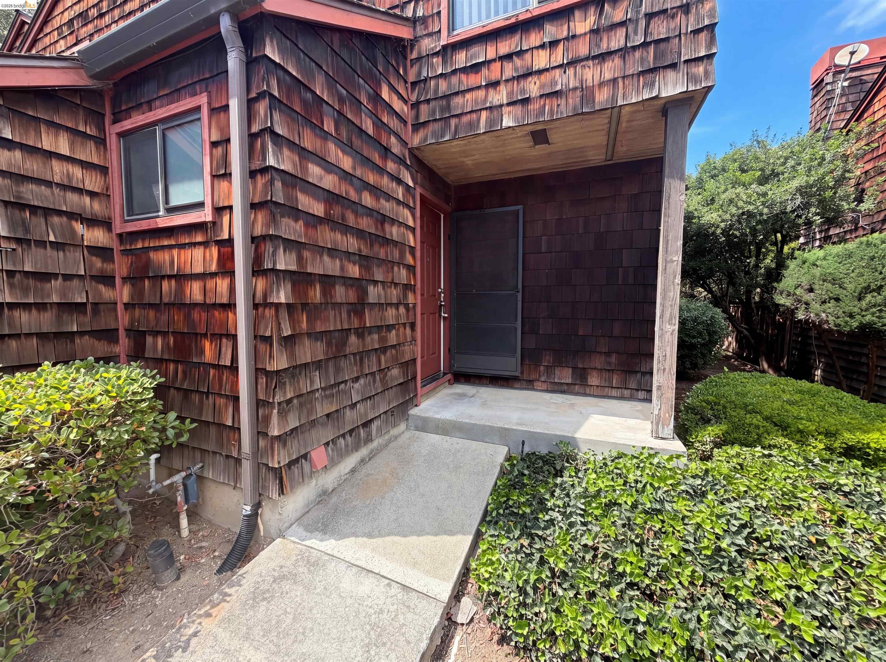 1555 Hecker Pass Road, Unit C101 Gilroy, CA 95020 - Photo 13 of 18 Wood shingle exterior featuring a covered entry, concrete walkway, and established perimeter landscaping