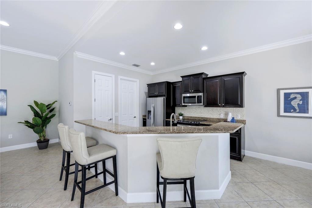 9062 Limestone Lane Naples, FL 34120 - Photo 11 of 48 a kitchen with stainless steel appliances kitchen island granite countertop a sink and a stove
