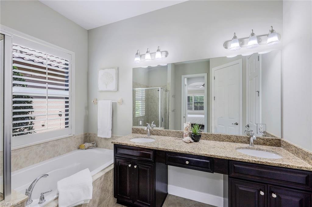 9062 Limestone Lane Naples, FL 34120 - Photo 15 of 48 a bathroom with a granite countertop sink a large mirror and a bathtub
