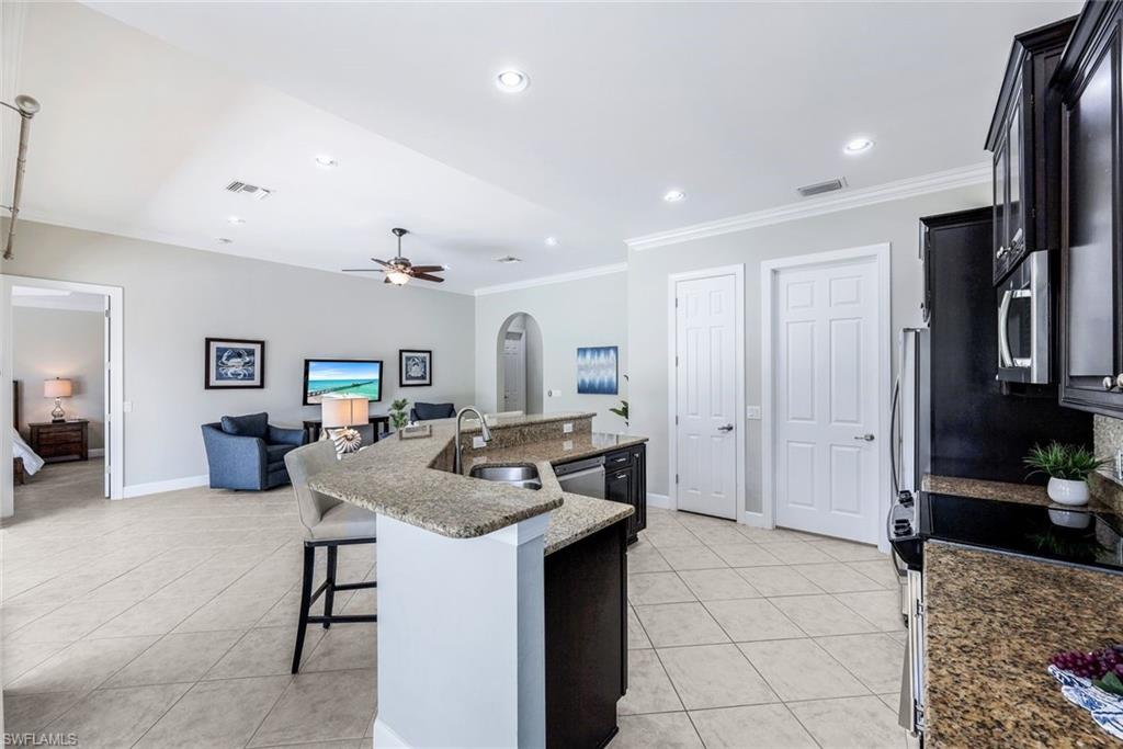 9062 Limestone Lane Naples, FL 34120 - Photo 10 of 48 a kitchen with kitchen island granite countertop a sink and a refrigerator
