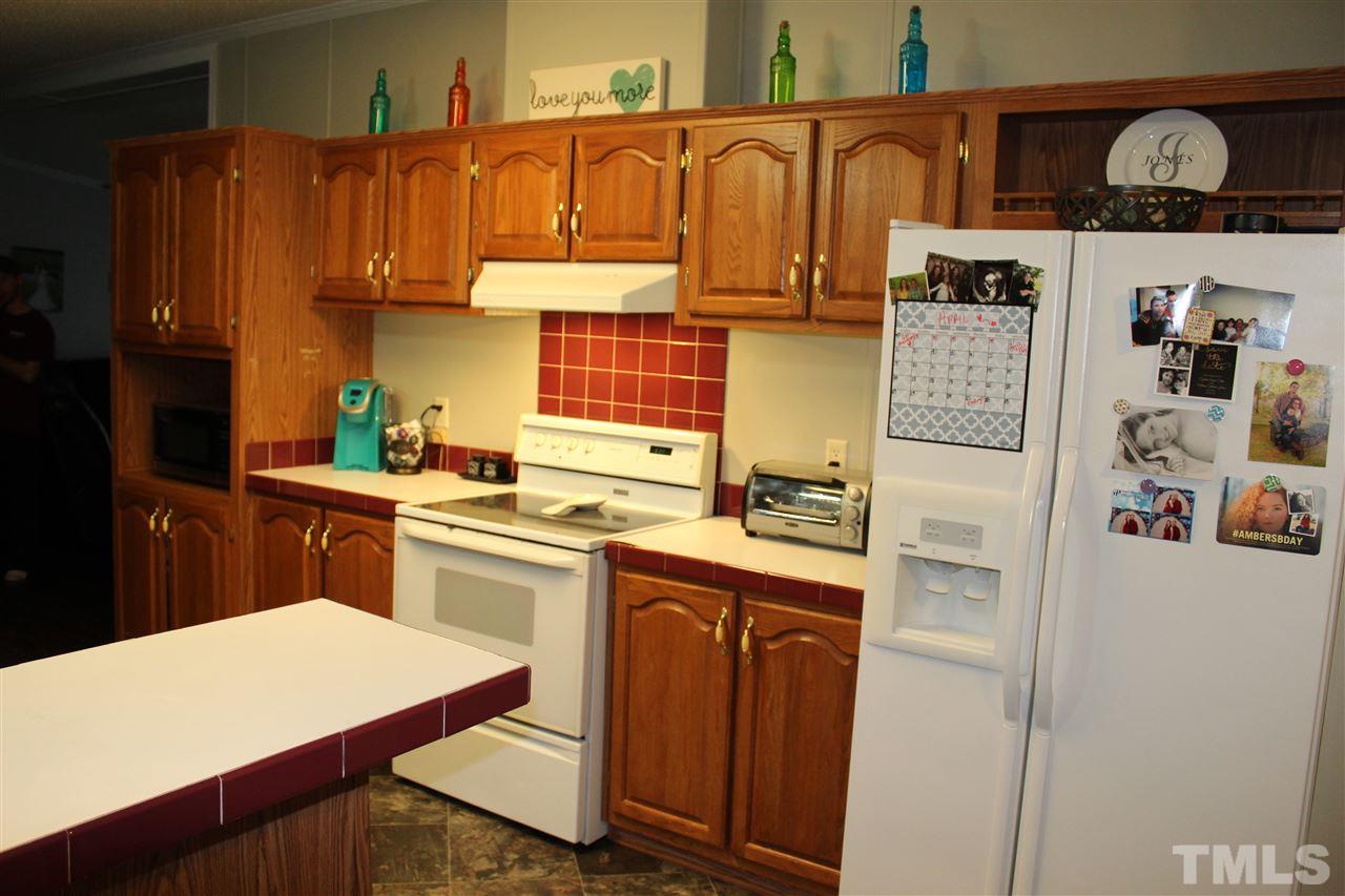 1189 Little Mountain Road Stem, NC 27581 - Photo 11 of 17 a kitchen with stainless steel appliances granite countertop a refrigerator a sink dishwasher and white cabinets with wooden floor