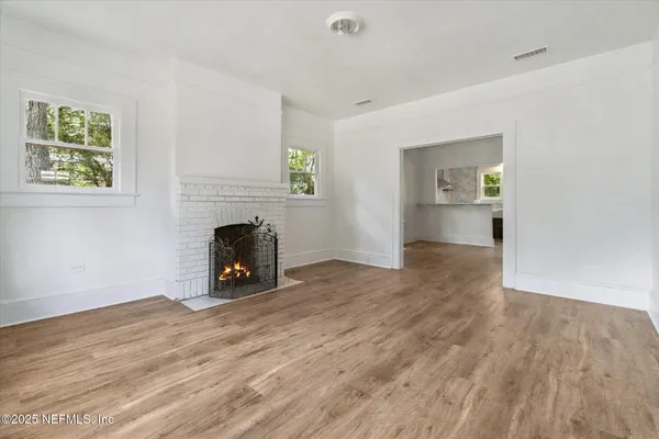 a view of empty room with wooden floor and a fireplace