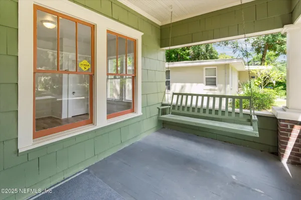 a view of a porch with a floor to ceiling window and a yard