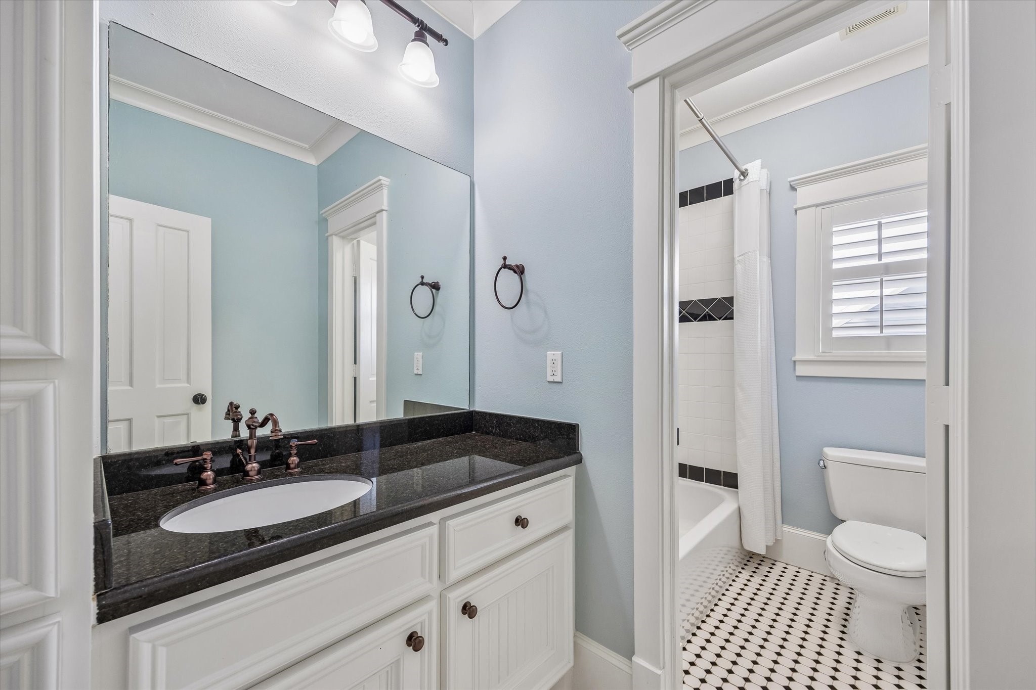 634 West 17th Street Houston, TX 77008 - Photo 23 of 42 This full bathroom hits the high notes with classic black and white tile details, wood shuttered windows, a granite-topped vanity with a full mirror and stylish vanity lights above, a storage tower for linens and other necessities, and a private water closet with a tub/shower combo.