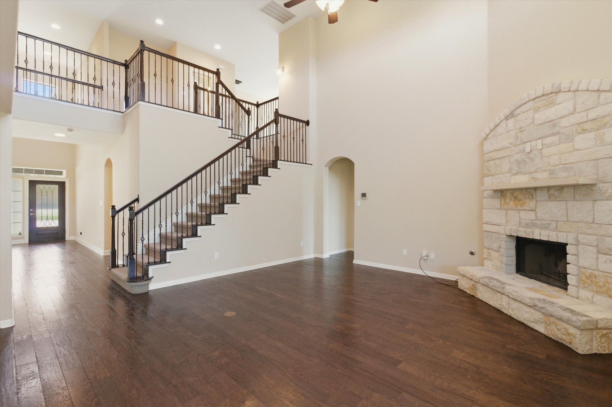 1511 Rimstone Drive Cedar Park, TX 78613 - Photo 12 of 39 Grand two-story living area features a stone fireplace, dark hardwood floors, and an elegant wrought iron staircase.