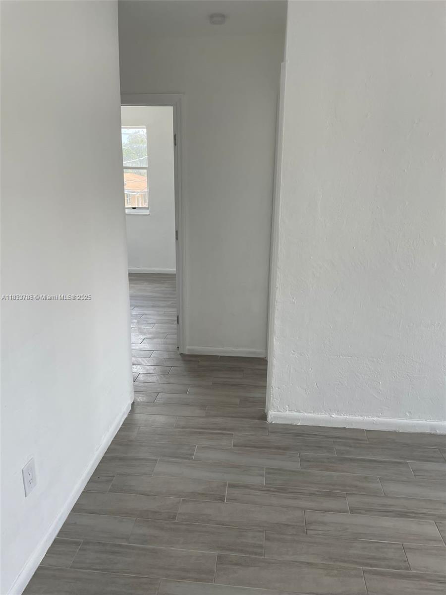 1261 Northwest 59th Street, Unit 5 Miami, FL 33142 - Photo 6 of 7 a view of a room with wooden floor and white walls