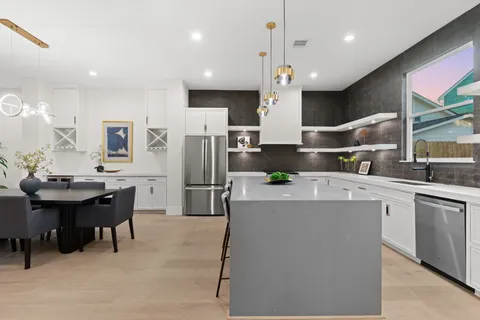 a kitchen with stainless steel appliances kitchen island a table chairs in it and wooden floors
