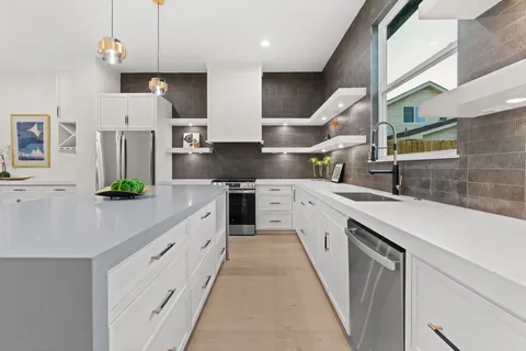 a large kitchen with stainless steel appliances kitchen island granite countertop a sink a stove and cabinets