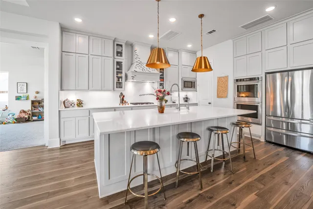 a kitchen with stainless steel appliances granite countertop a table chairs refrigerator and sink