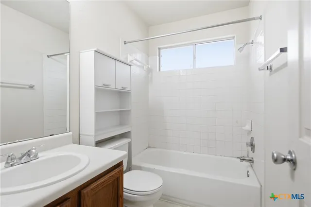 a bathroom with a granite countertop bathtub shower sink vanity and toilet