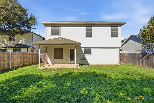 a white house with a small yard and trees