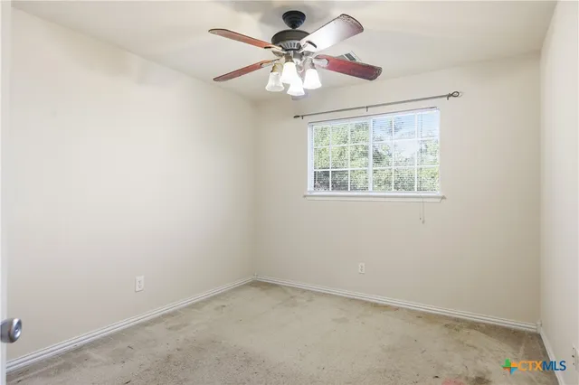 an empty room with a window and a fan