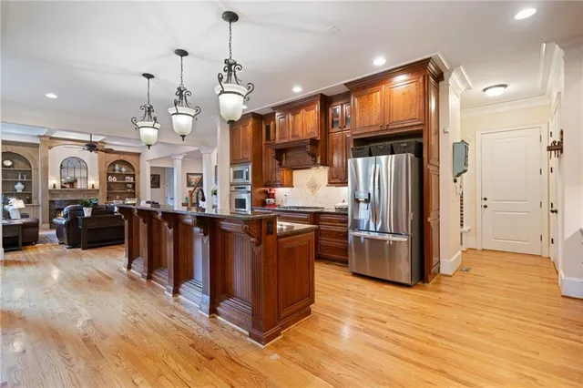 a kitchen with stainless steel appliances kitchen island granite countertop a refrigerator a stove and a wooden floors