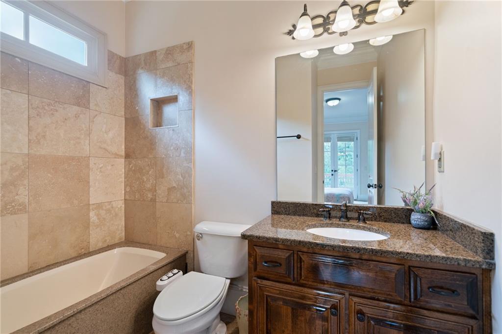 1750 Cone Flower Way Suwanee, GA 30024 - Photo 46 of 58 a bathroom with a granite countertop toilet a sink and a mirror