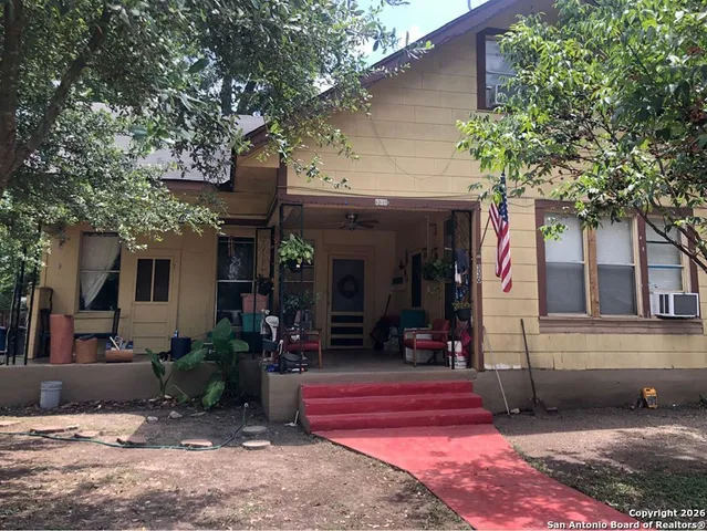 a view of a house with a tree and wooden fence