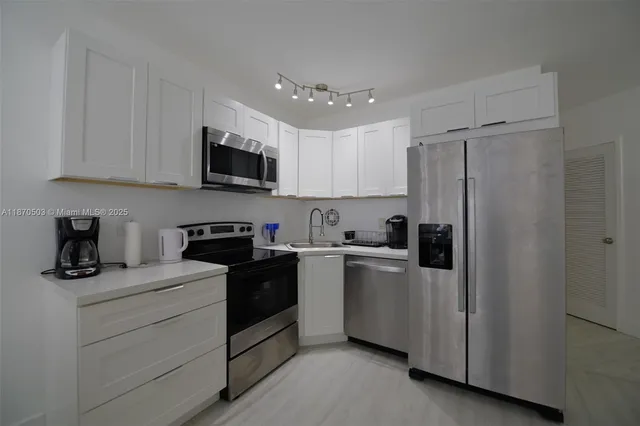 a kitchen with white cabinets and stainless steel appliances