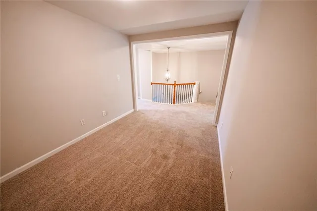 an empty room with a chandelier fan and windows