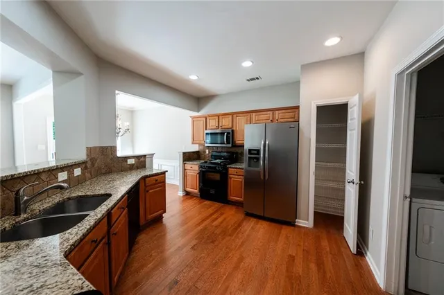 a kitchen with stainless steel appliances granite countertop a refrigerator a sink dishwasher a stove with wooden floor and cabinets