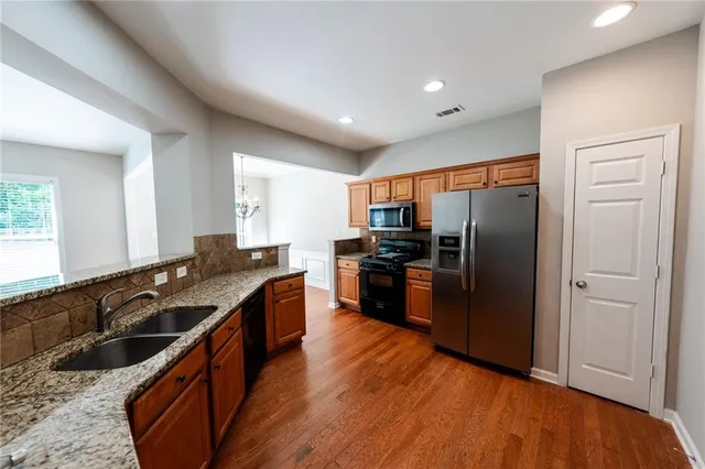 a kitchen with granite countertop stainless steel appliances a refrigerator cabinets and wooden floor
