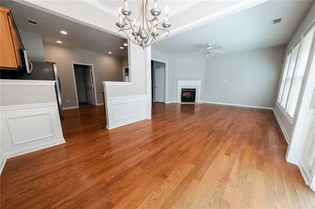 a view of a livingroom with wooden floor and a kitchen