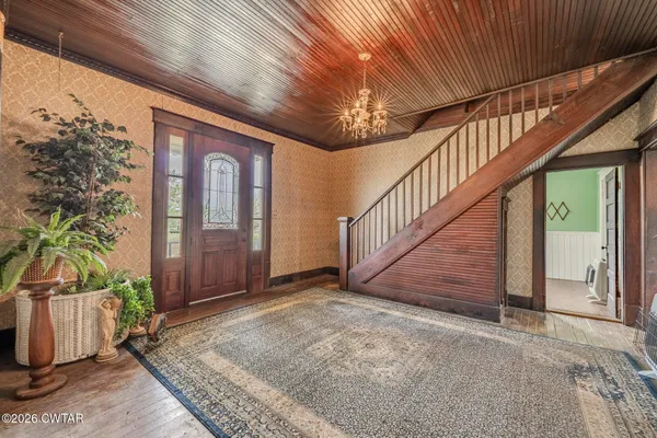 an empty room with chandelier fan and windows