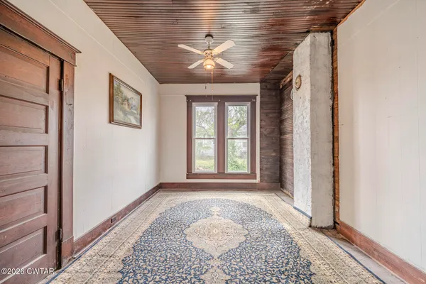 a view of a hallway with wooden floor and a chandelier fan