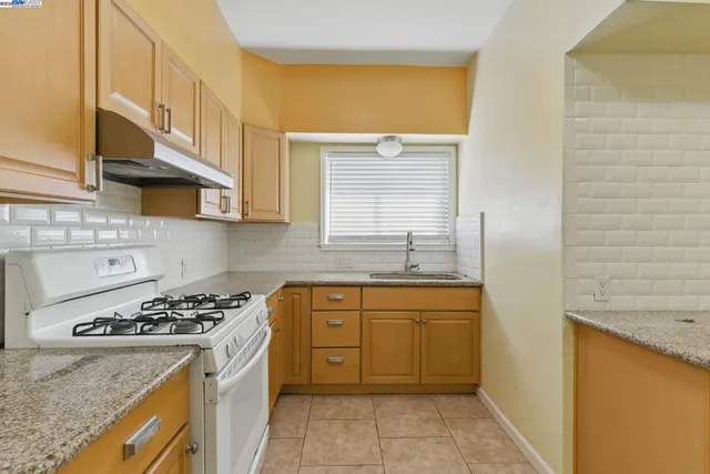 a kitchen with stainless steel appliances granite countertop a sink a stove and a refrigerator