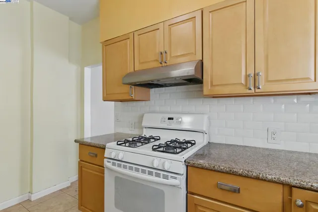 a kitchen with granite countertop a stove and a white cabinets