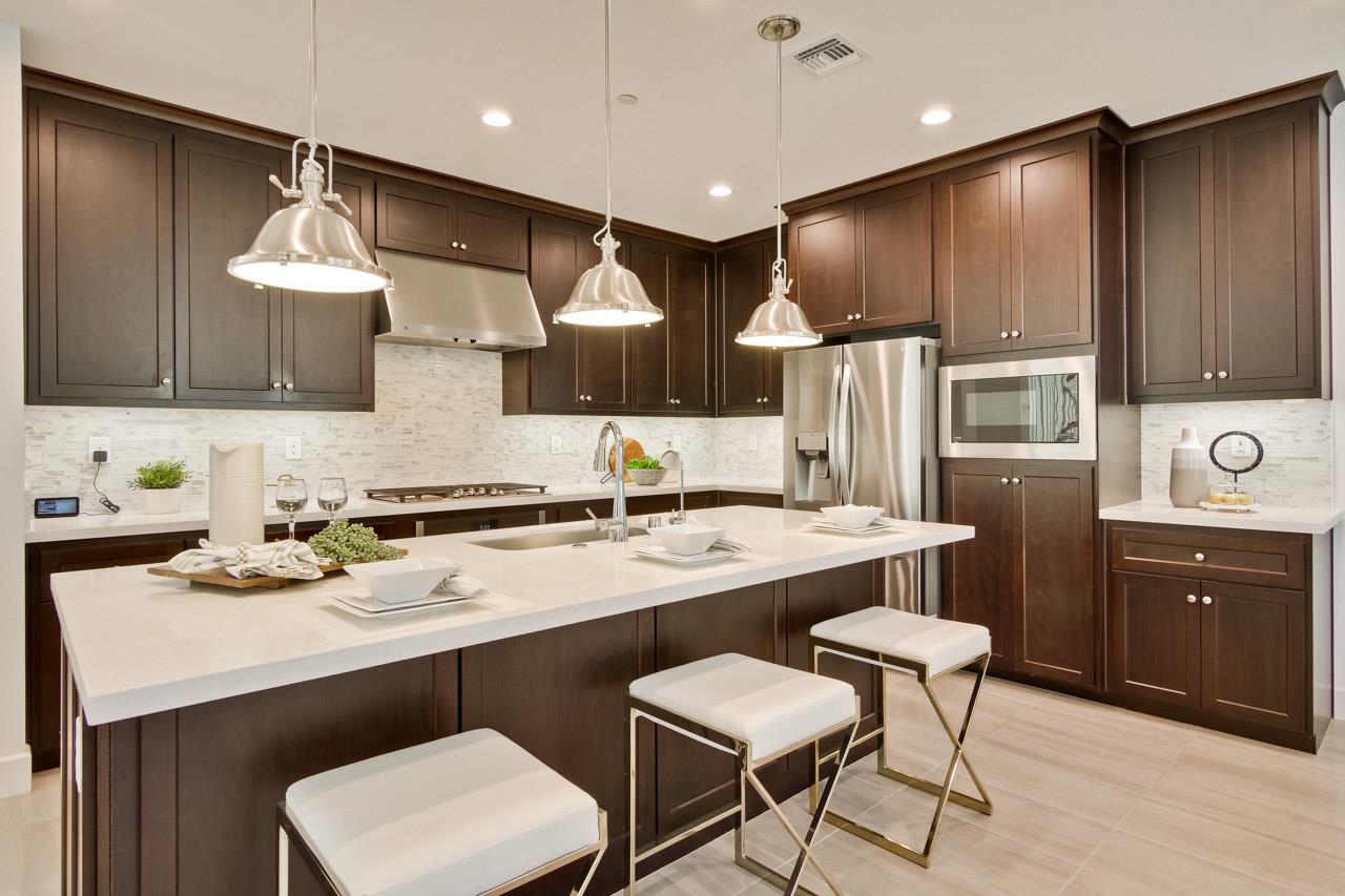 a kitchen with a sink stainless steel appliances and chairs