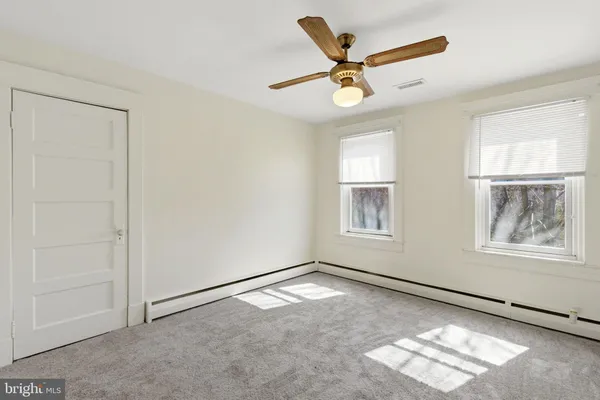 an empty room with windows and fan