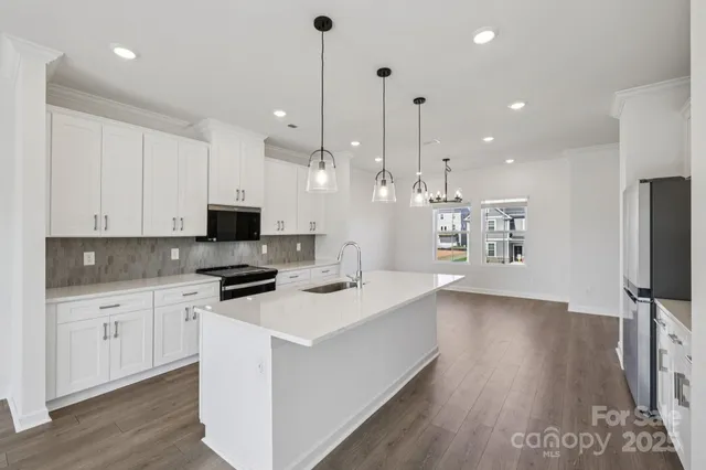 a kitchen with stainless steel appliances kitchen island granite countertop a stove a sink and a refrigerator with wooden floor