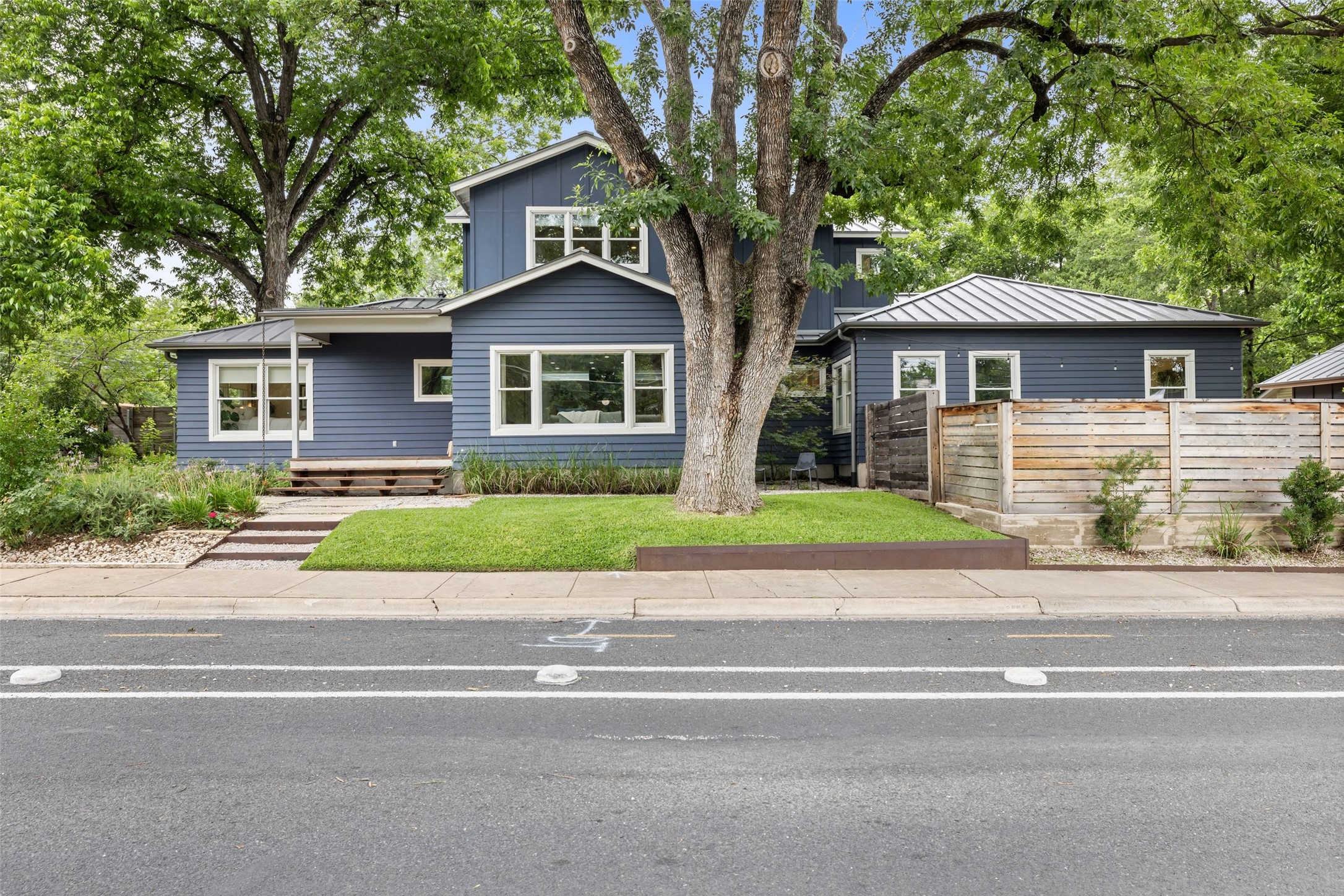 2000 Rundell Place Austin, TX 78704 - Photo 1 of 38 Mature trees frame this charming residence with dark siding, a metal roof, and a low-maintenance landscape.
