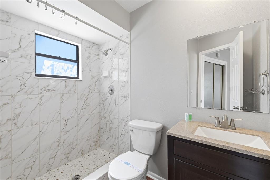 5364 Deltona Boulevard Spring Hill, FL 34606 - Photo 13 of 33 a bathroom with a toilet sink vanity and mirror