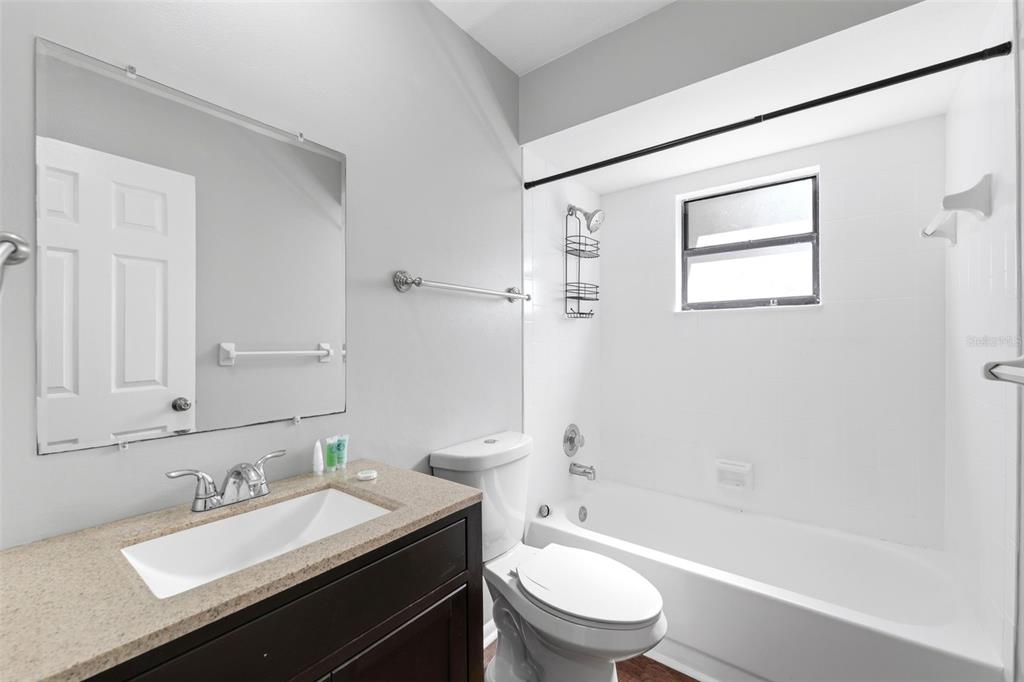 5364 Deltona Boulevard Spring Hill, FL 34606 - Photo 17 of 33 a bathroom with a granite countertop sink toilet a mirror and shower