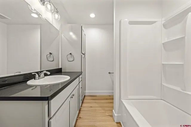 a bathroom with a granite countertop sink a toilet a mirror and shower
