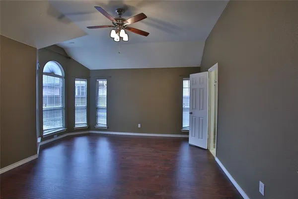 a view of an empty room with a window and wooden floor